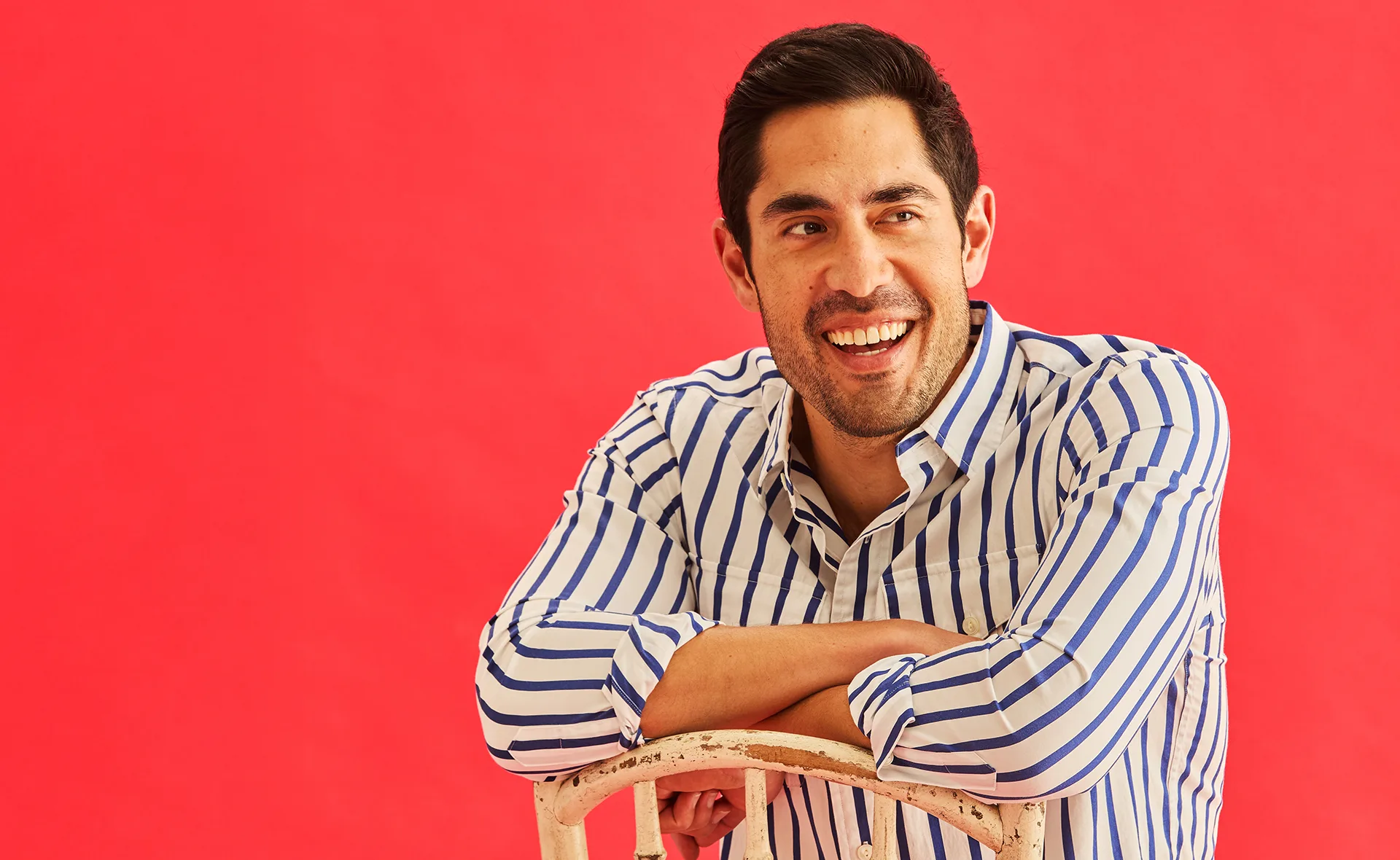 Tai Hara in a black and white stripe shirt against a red backdrop.