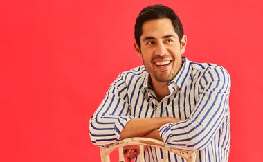 Tai Hara in a black and white stripe shirt against a red backdrop.