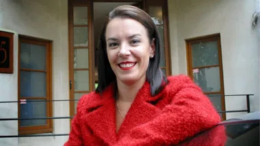 A woman in a red blazer who is smiling