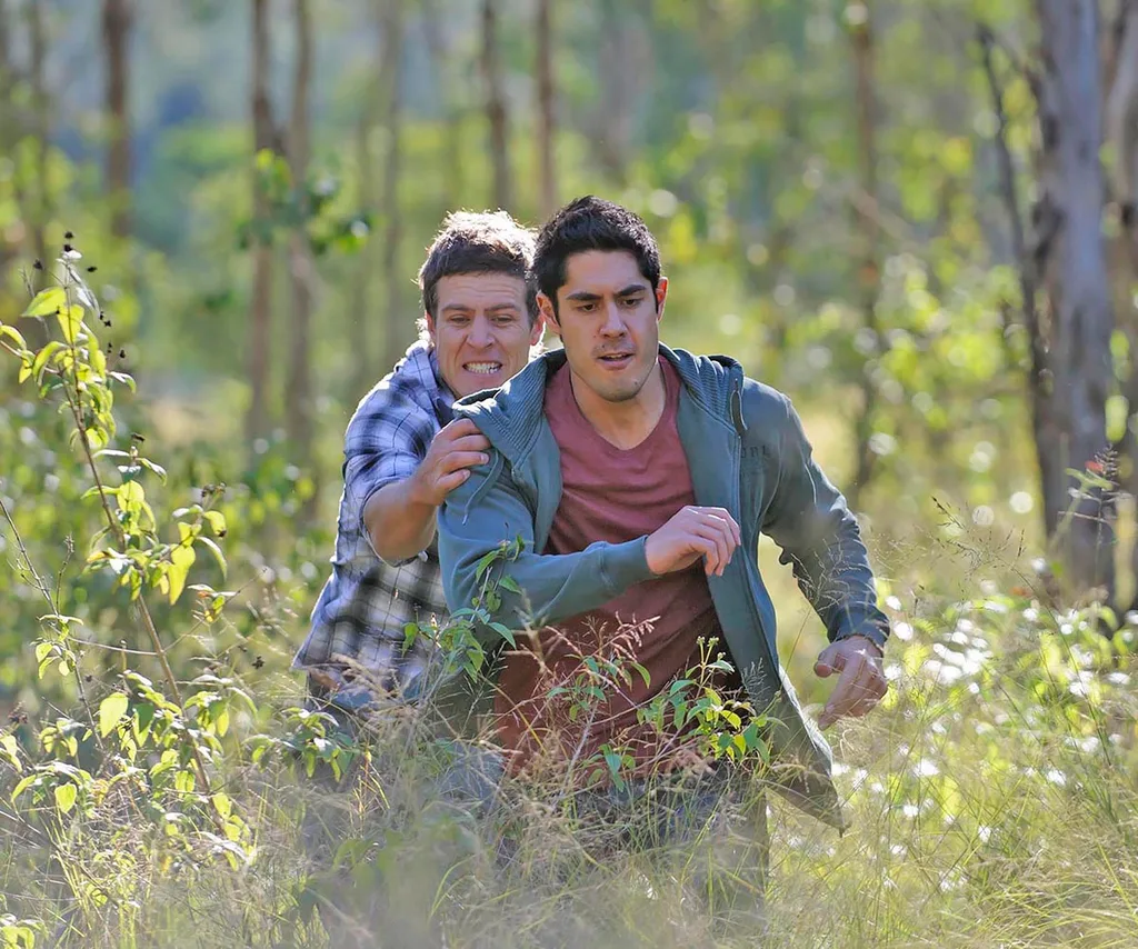 Stephen Peacocke and Tai Hara running in the bush in a scene for Home and Away.
