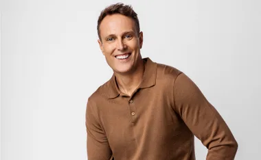 Matt Shirvington, in a brown shirt, smiles at the camera
