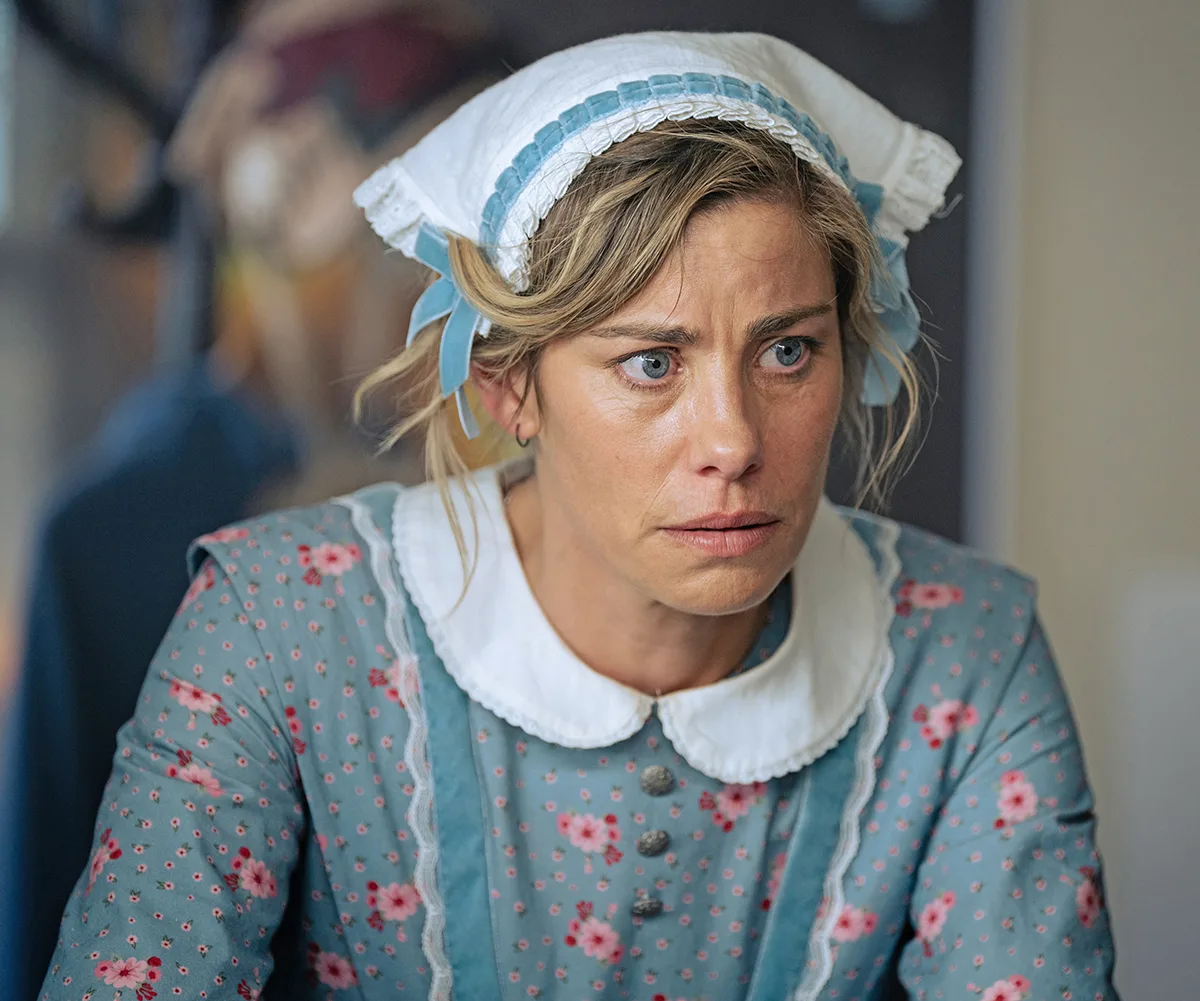 Brooke Satchwell, wearing a bonnet and an old-style dress, has a concerned look on her face