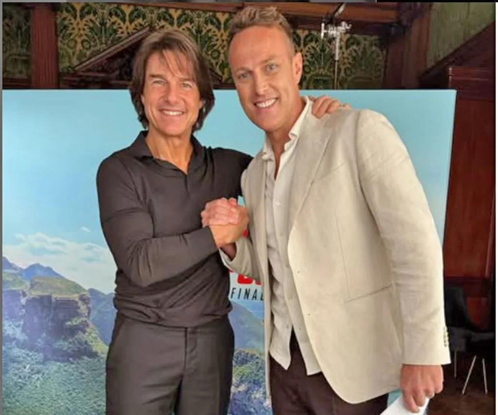 Matt stands next to Tom Cruise, who is holding Matt's hand and has another hand on Matt's shouder