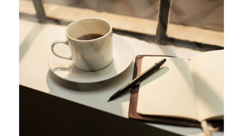 A cup of coffee sits alongside a blank journal.