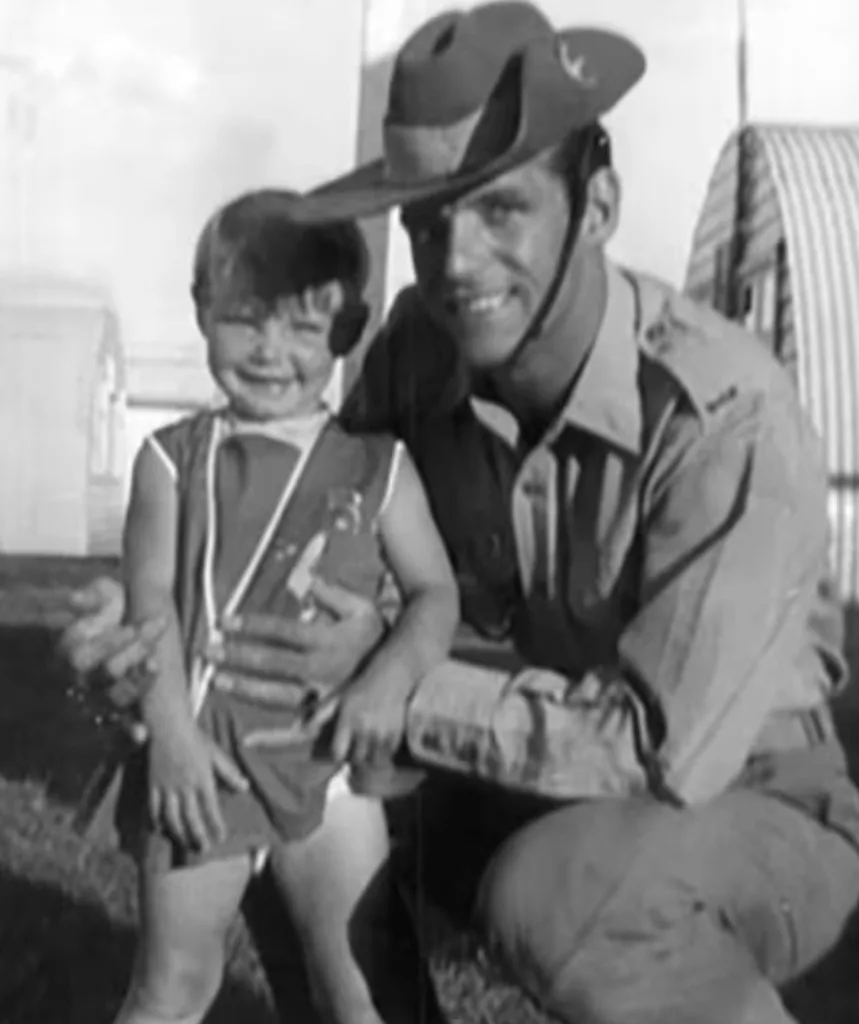 A black and white image of a small child and a man in army uniform.