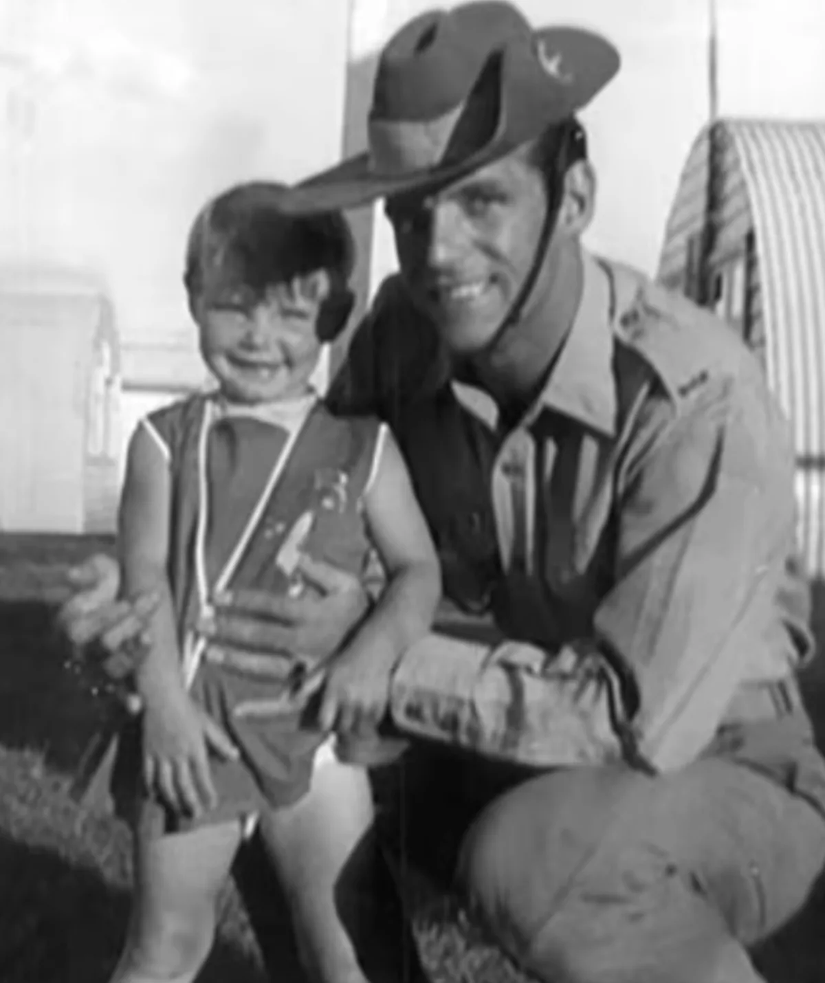 A black and white image of a small child and a man in army uniform.