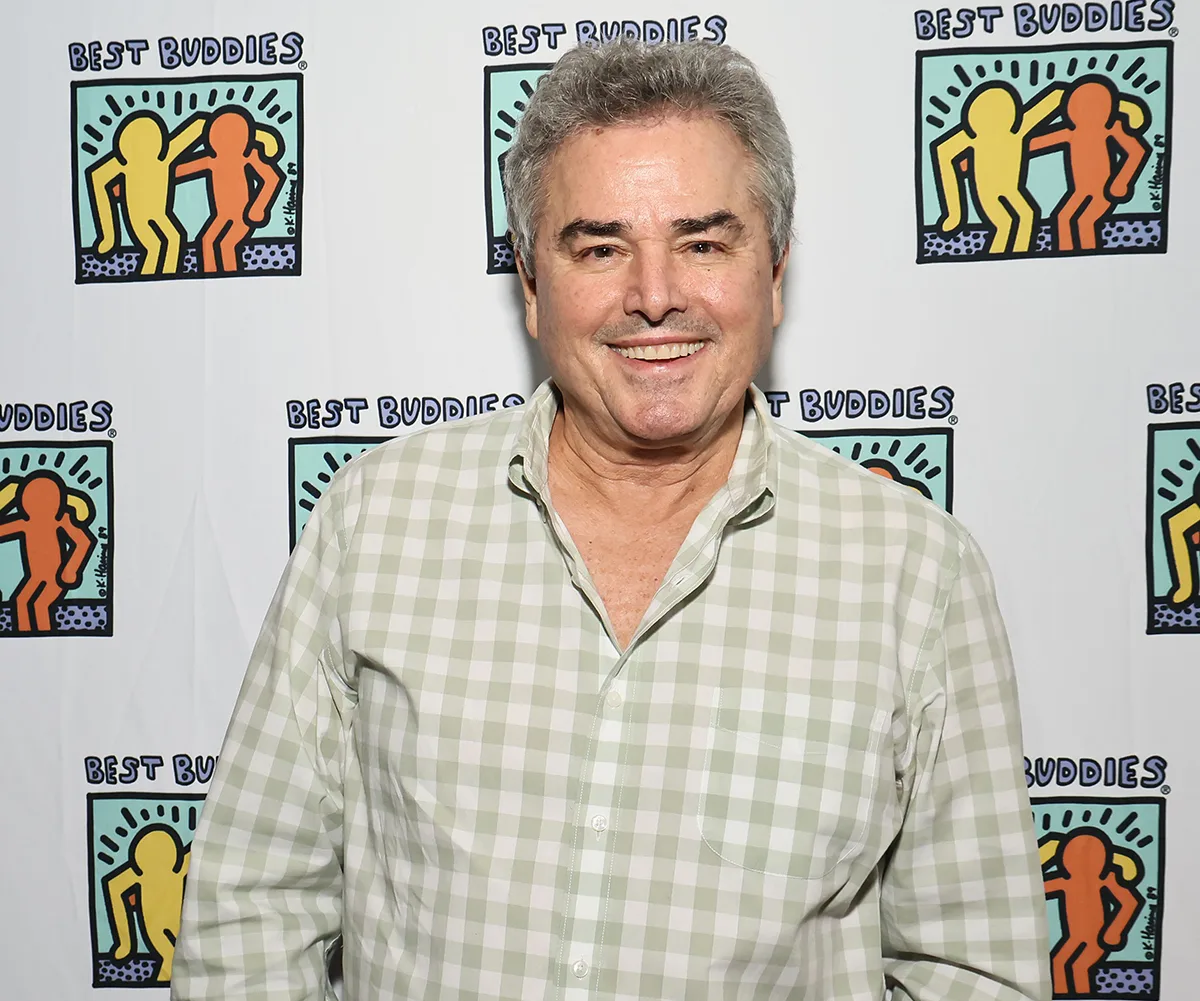 Christopher, wearing a checked shirt, poses at an event