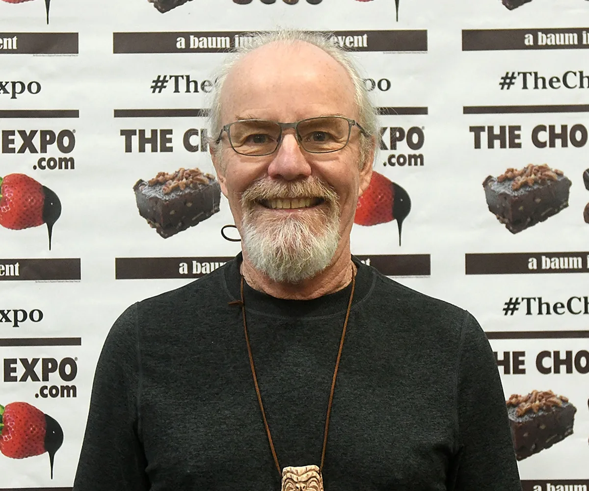 Mike Lookinland, with glasses and a beard and wearing a black shirt, poses at an event