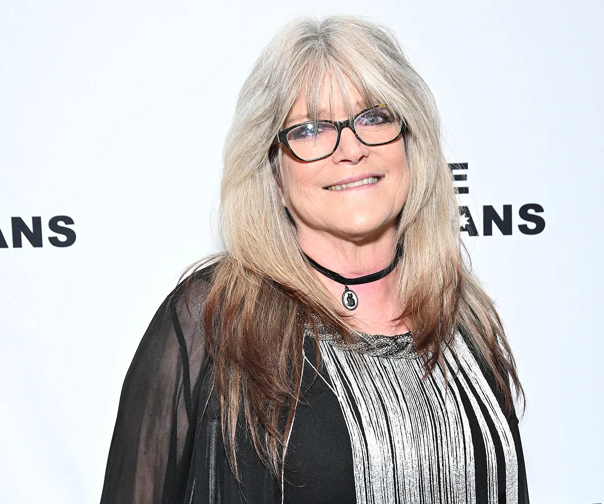 Susan Olsen, with glasses and white hair, poses at an event