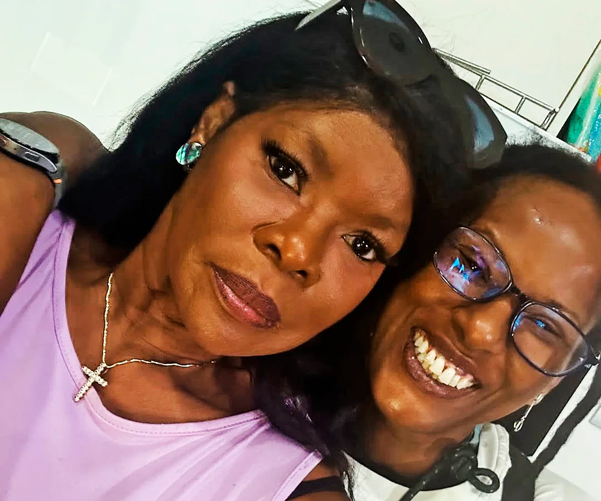 Marcia Hines, in purple, with her daughter Deni, wearing glasses, their two faces very close together