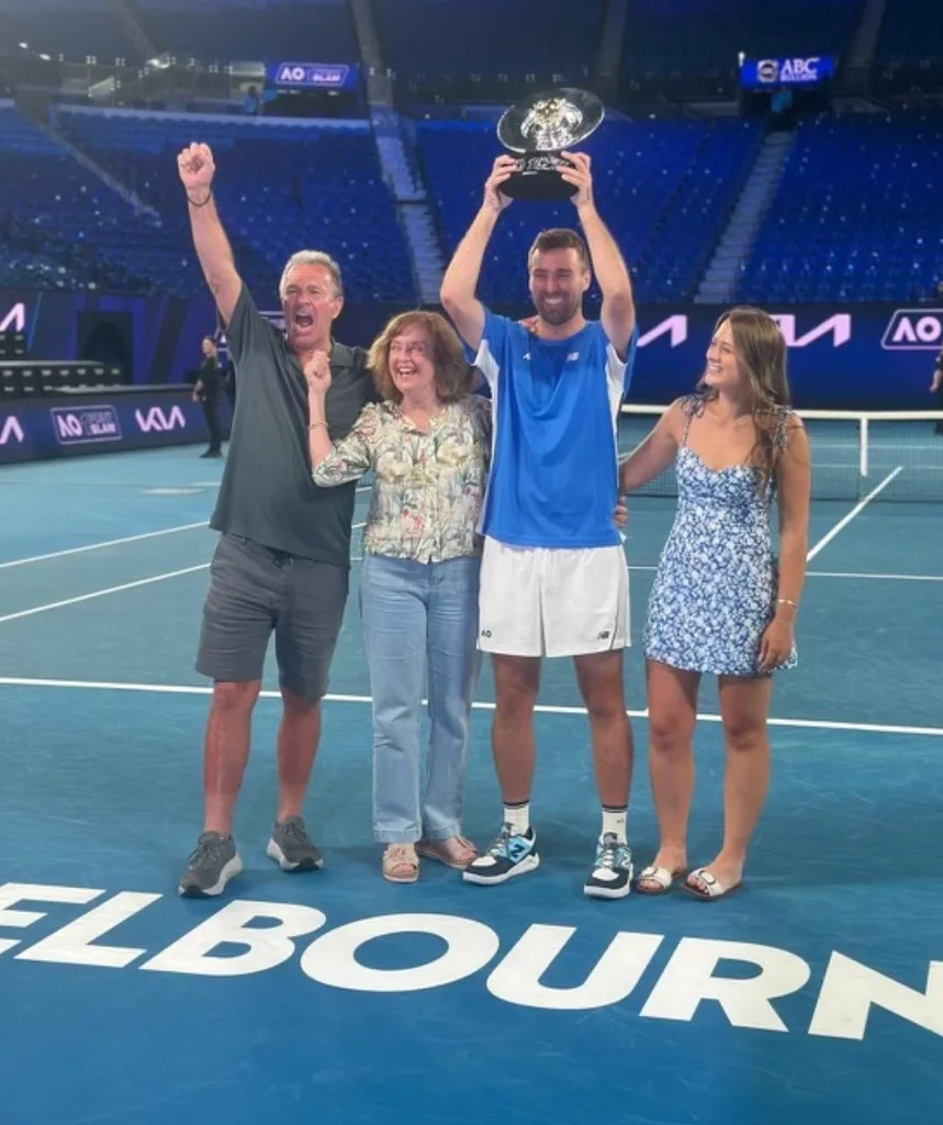 A family standing on a tennis court celebrating