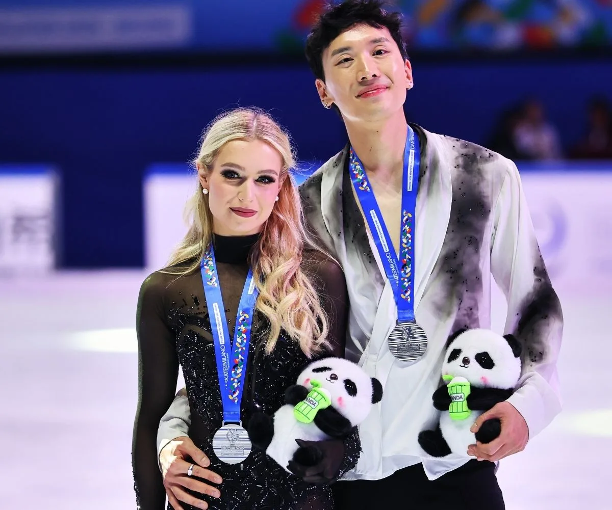 A man and woman with medals around their necks holding stuffed toys