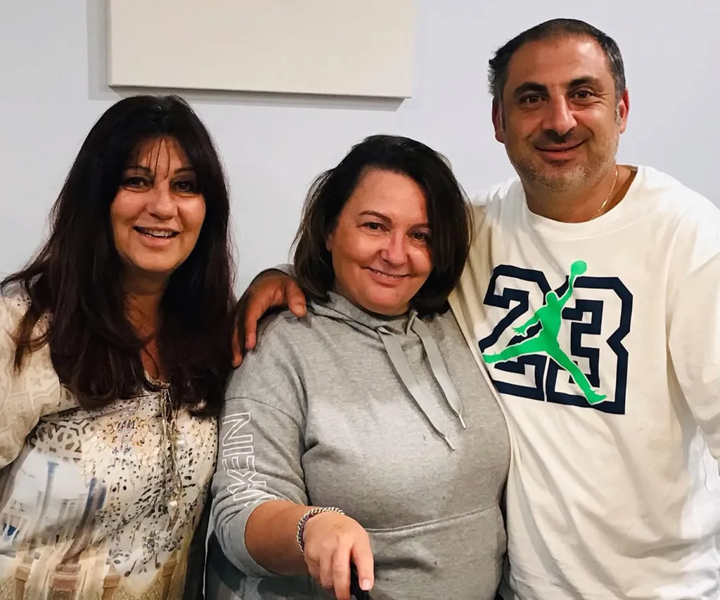 Anastasia, wearing grey, stands in between Faye and her fiance Gabriel, who has the number 23 on his t-shirt