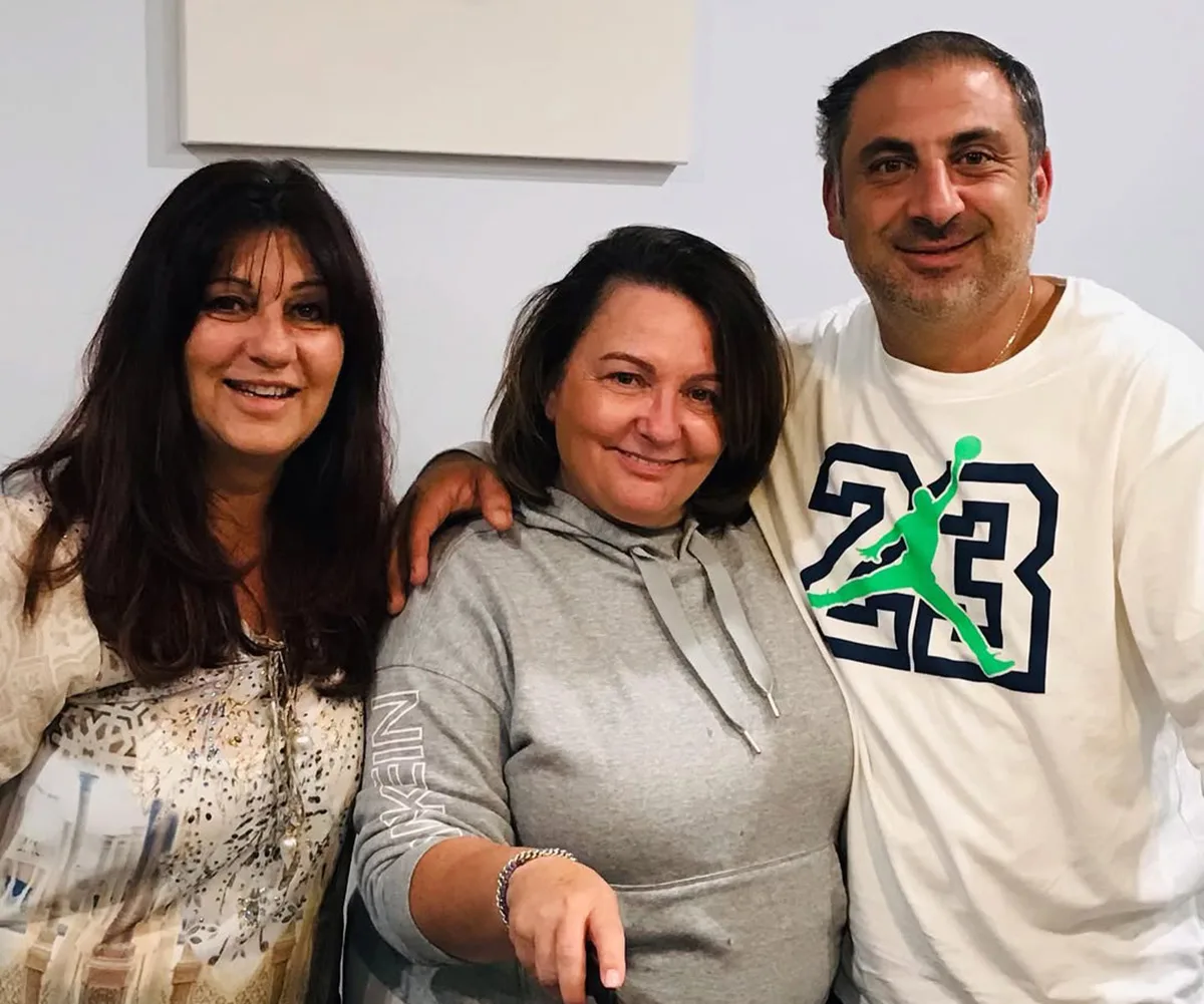 Anastasia, wearing grey, stands in between Faye and her fiance Gabriel, who has the number 23 on his t-shirt