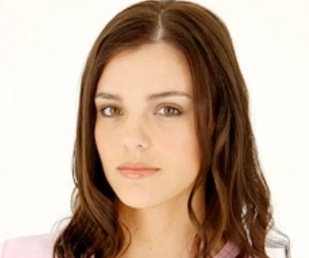 A close-up shot of Gemma, with her brown hair loose, in front of a white background