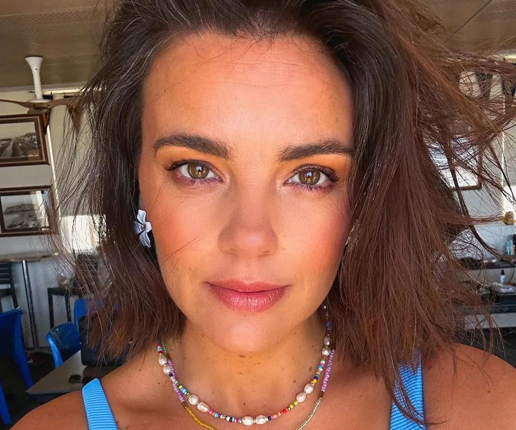 A close-up of Gemma, wearing a top with blue straps and a necklace