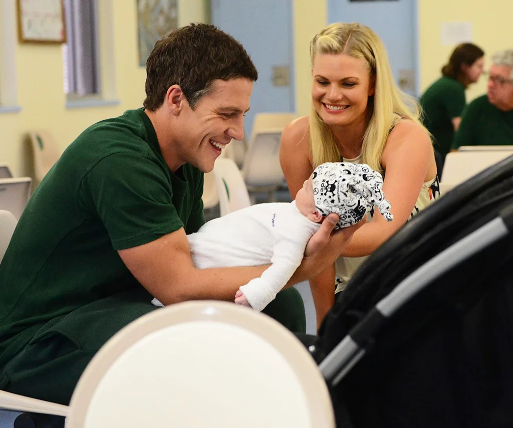 Stephen, in character as Brax, holds baby Casey, while Bonnie, in character as Ricky, looks on with a smile