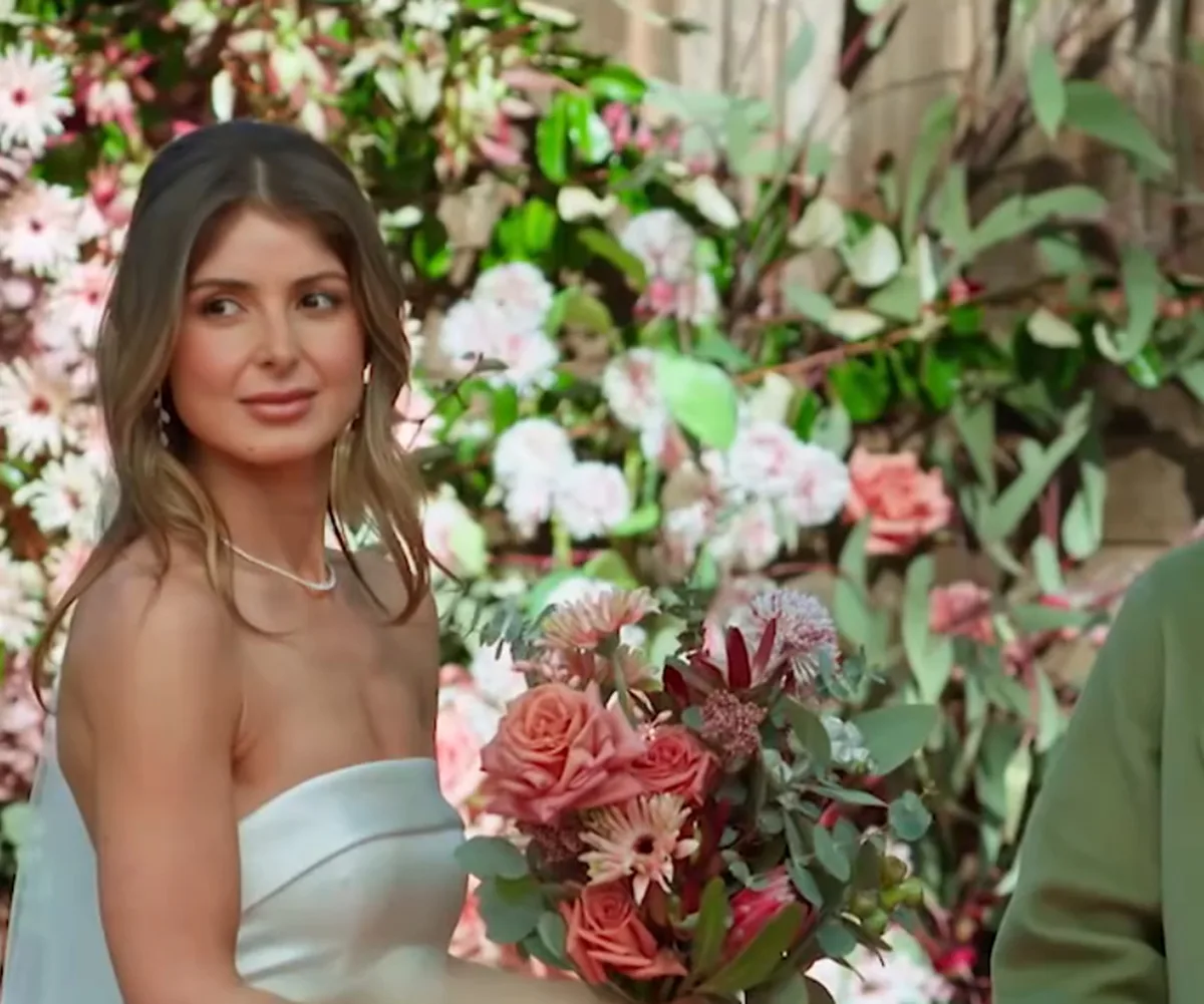 Mel from MAFS Australia season 13 pictured in her gown at the altar against a backdrop of flowers looking confused.