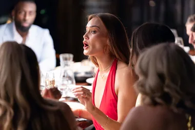 Brook in red dress talking to the table