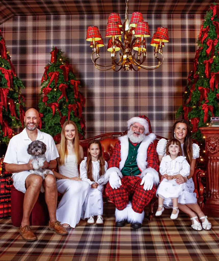 Gemma and family sit next to Santa on a couch in a room with tartan-covered walls