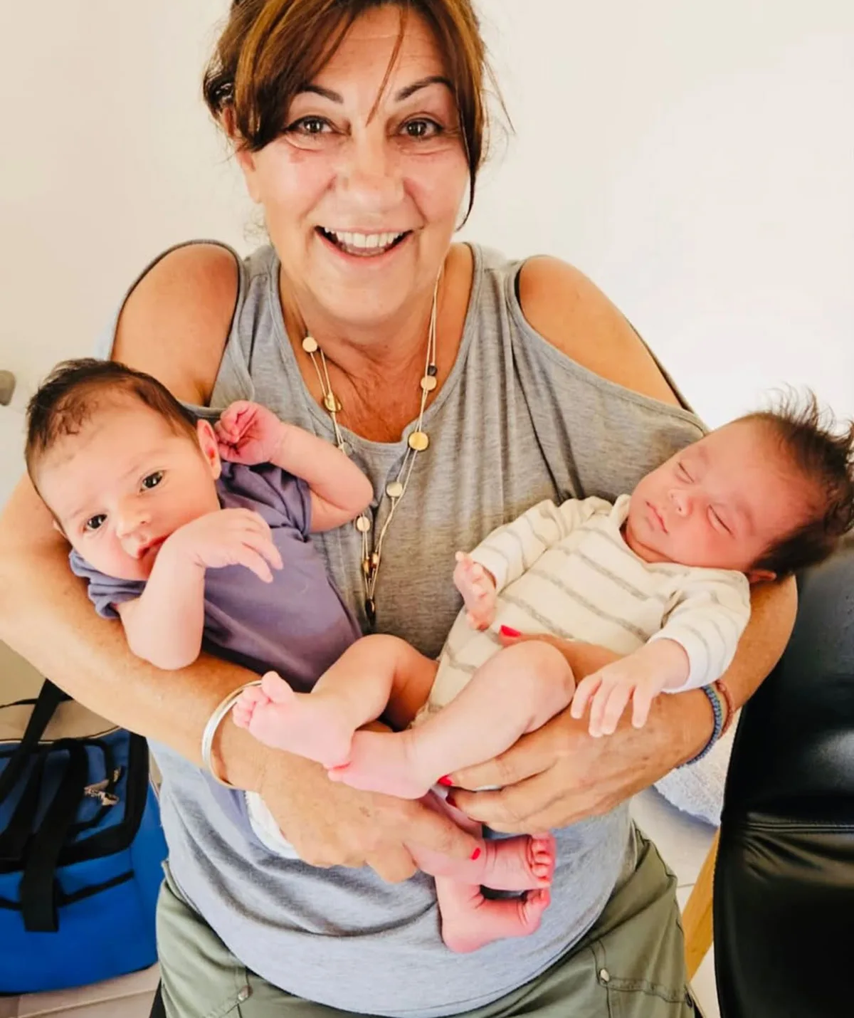 Faye, in a grey top, holds a baby in each arm