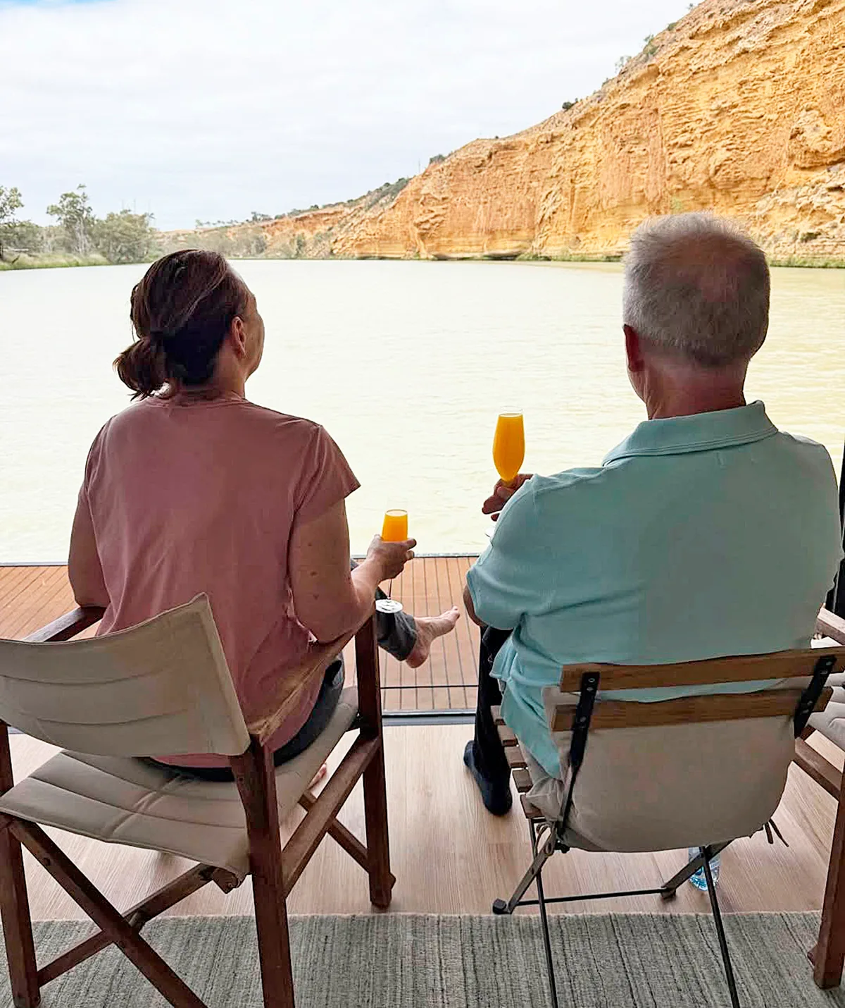 A shot of Lisa and Simon from behind, as they sit on chairs, looking out on the cliffs of the River Murray