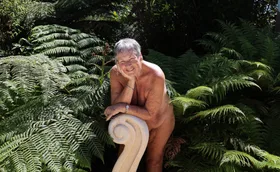 June Campbell-Tong with the Koru statue and garden she created and gifted to the naturist club she was a member of. (Image: Supplied)