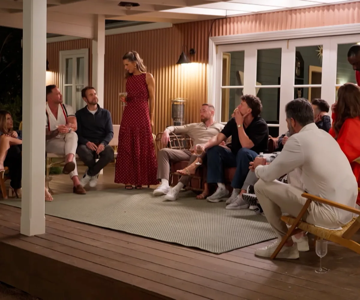 MAFS' Bec toasting the group in a red dress behind the house they are all holidaying in for the retreat.