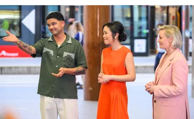 Guy, wearing a green shirt, stands next to Andrea Lam, in an orange dress, and Amanda Keller, in a pink dress, at Circular Quay