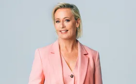 Amanda in a pink jacket, smiling, in front of a grey background
