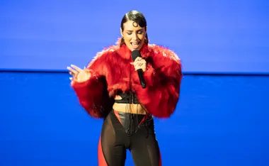 Australian Idol's Sophie performing on stage in a large fur red jacket.