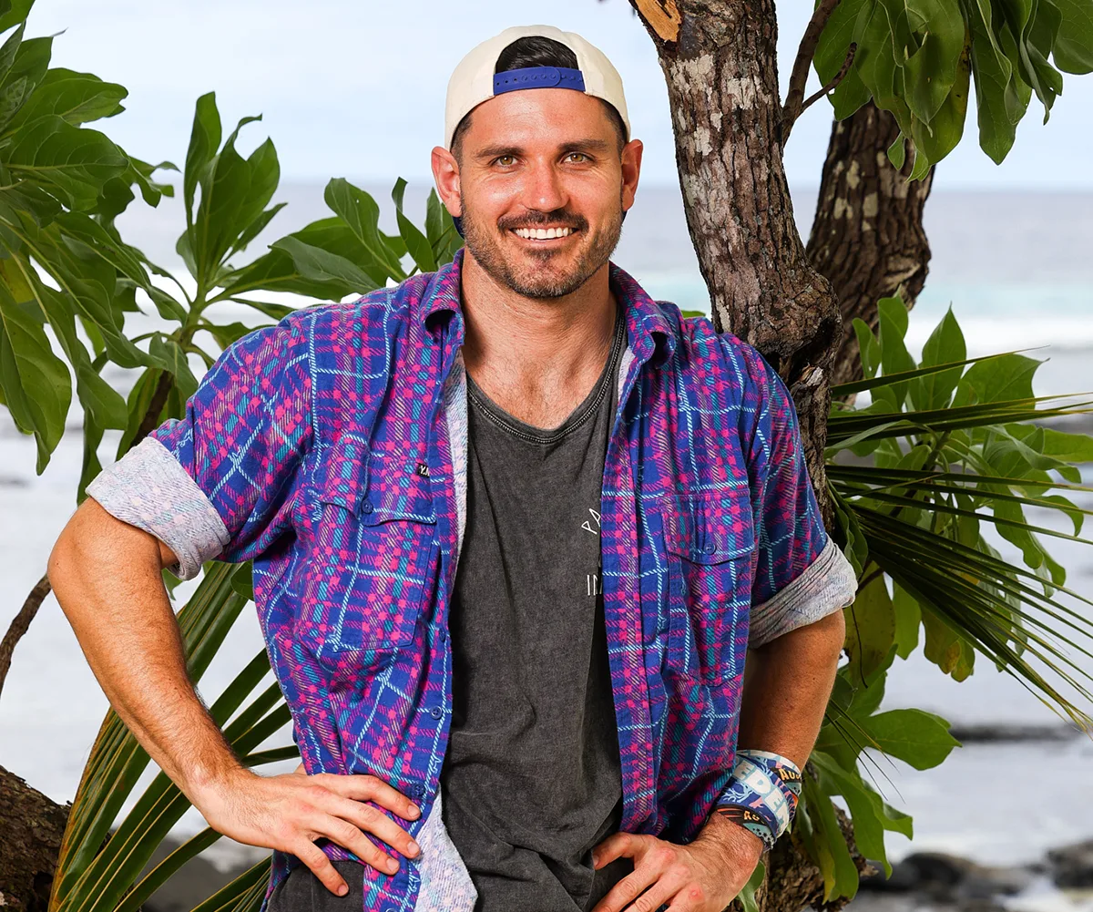 Simon, wearing a cap backwards and a blue shirt, on a beach in Samoa