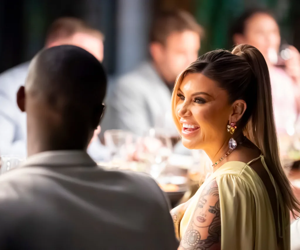 Gia smiling at the MAFS dinner party with hair up in a yellow dress.