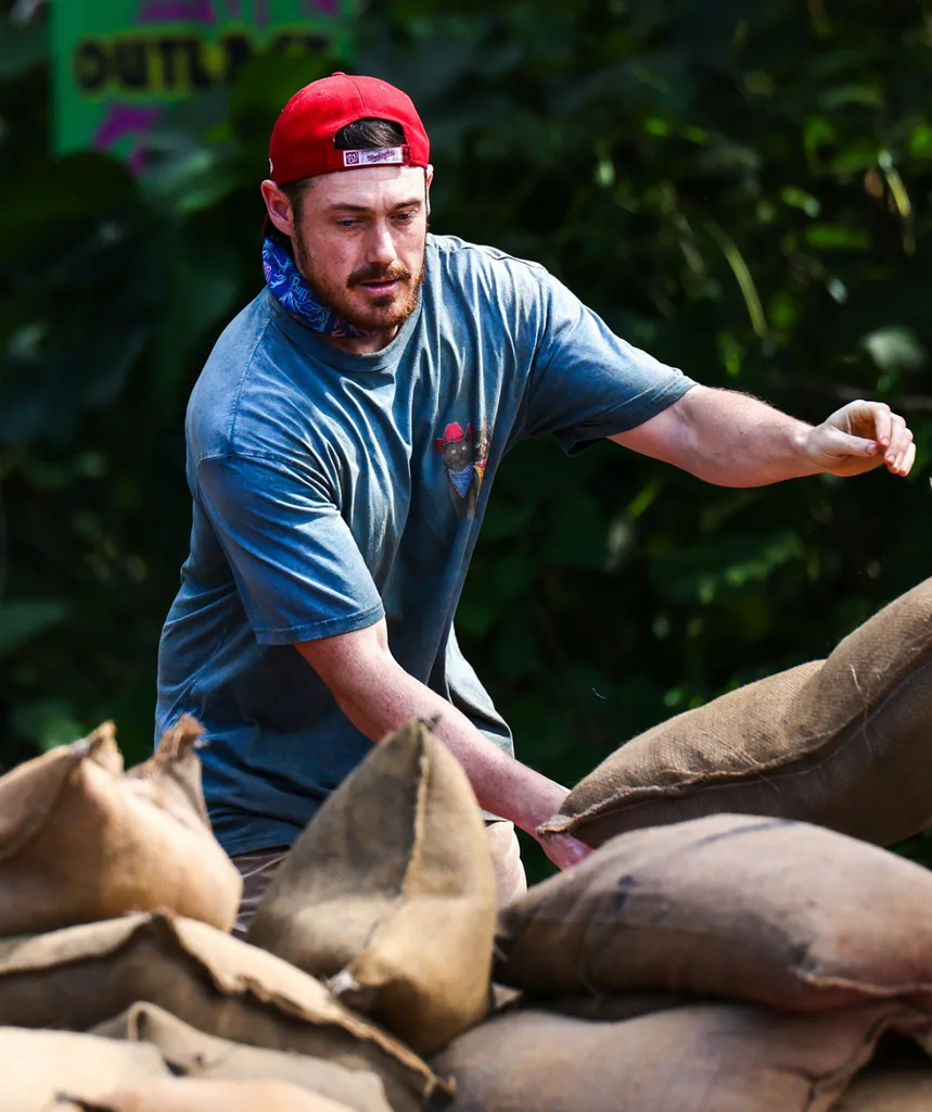 Harry, with a red bandana and a blue shirt, focuses on a challenge in Survivore
