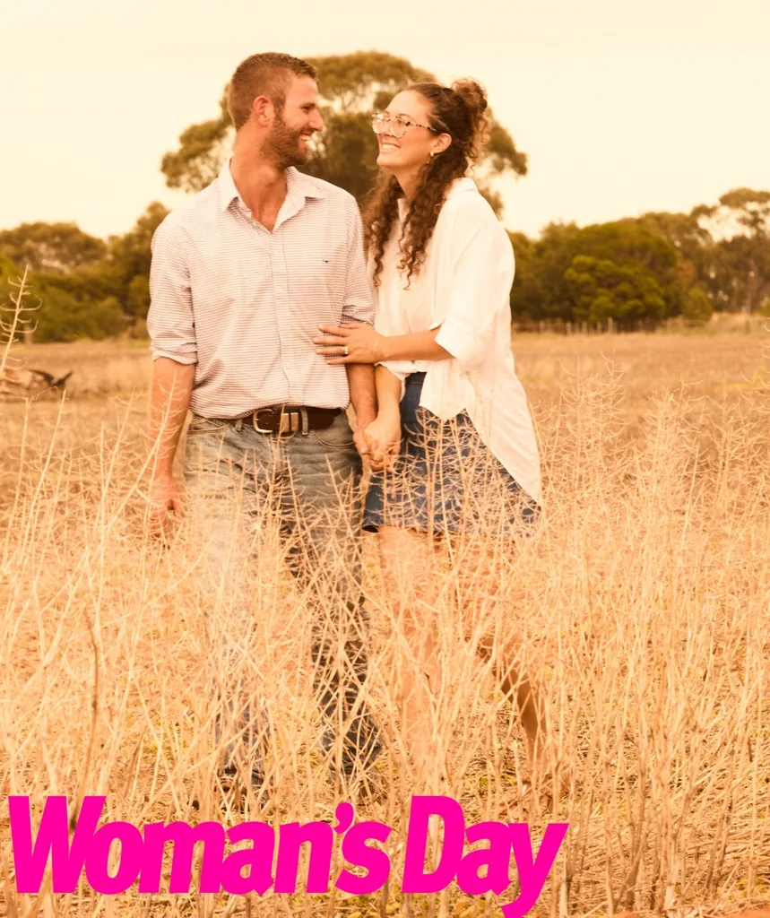 A man and woman in a field arm in arm.