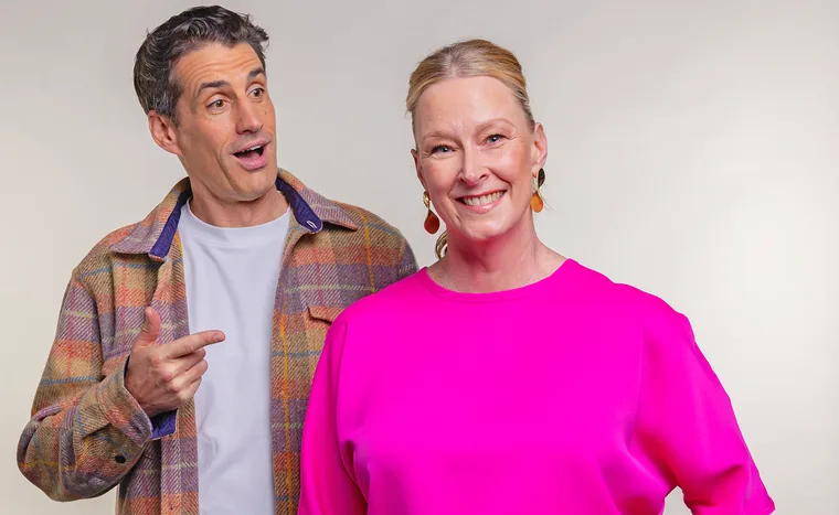 Andy Lee, wearing a white t-shirt and a checked shirt, points at Leigh Sales, in hot pink