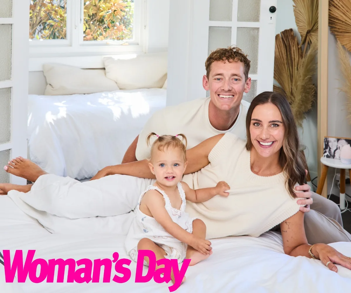 A girl toddler, man and woman smiling and cuddled up.