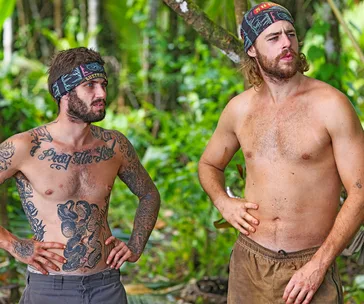 Jackson, wearing just shorts and a buff on his head, stands next to another Survivor player in Samoa