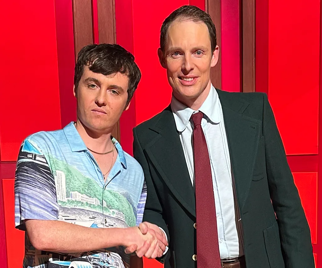 Sam Campbell, in a pale blue shirt, shakes hands with Guy Montgomery, in a black suit and red tie