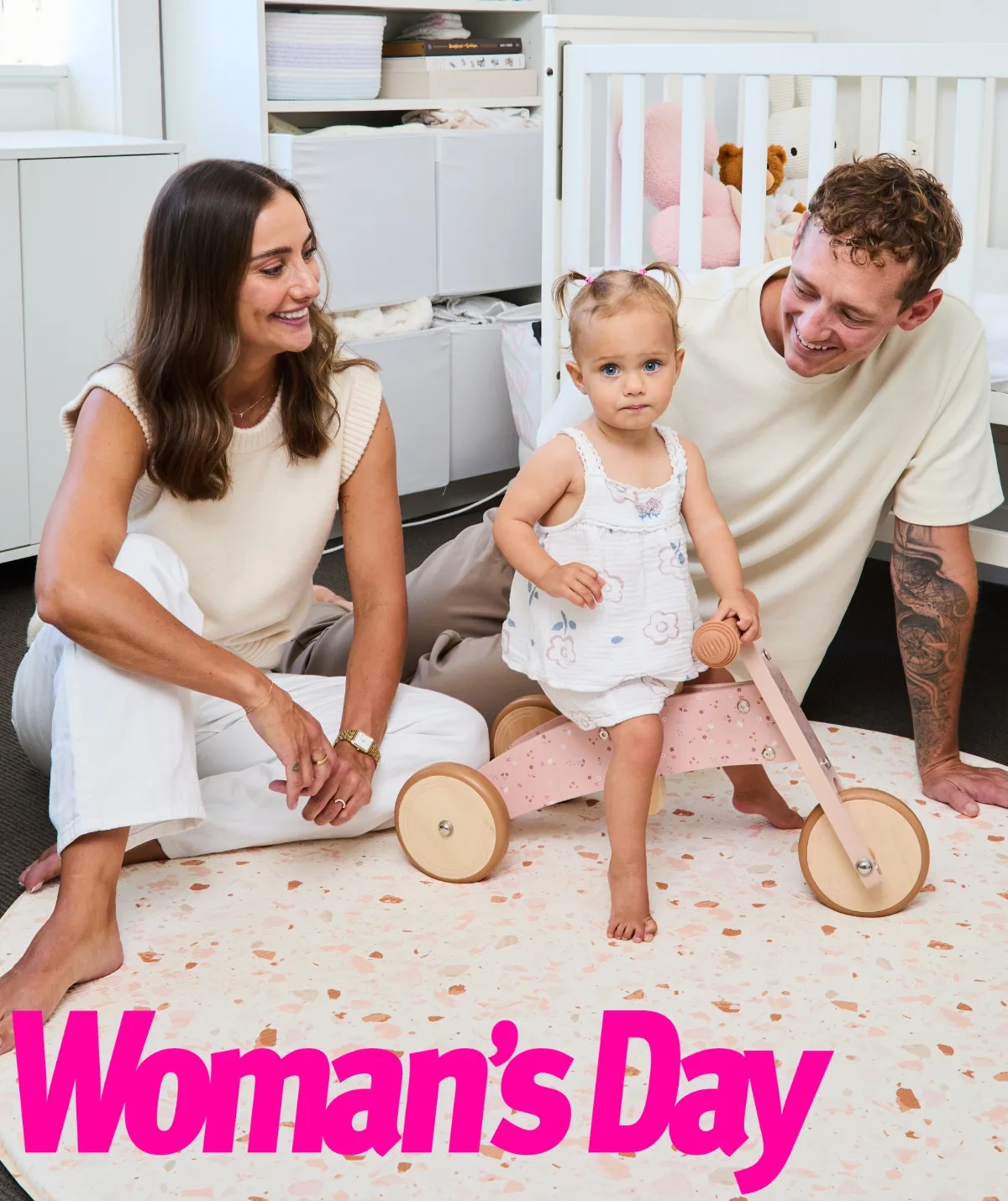 A young woman, toddler girl and young man sitting on the floor of a child's bedroom.