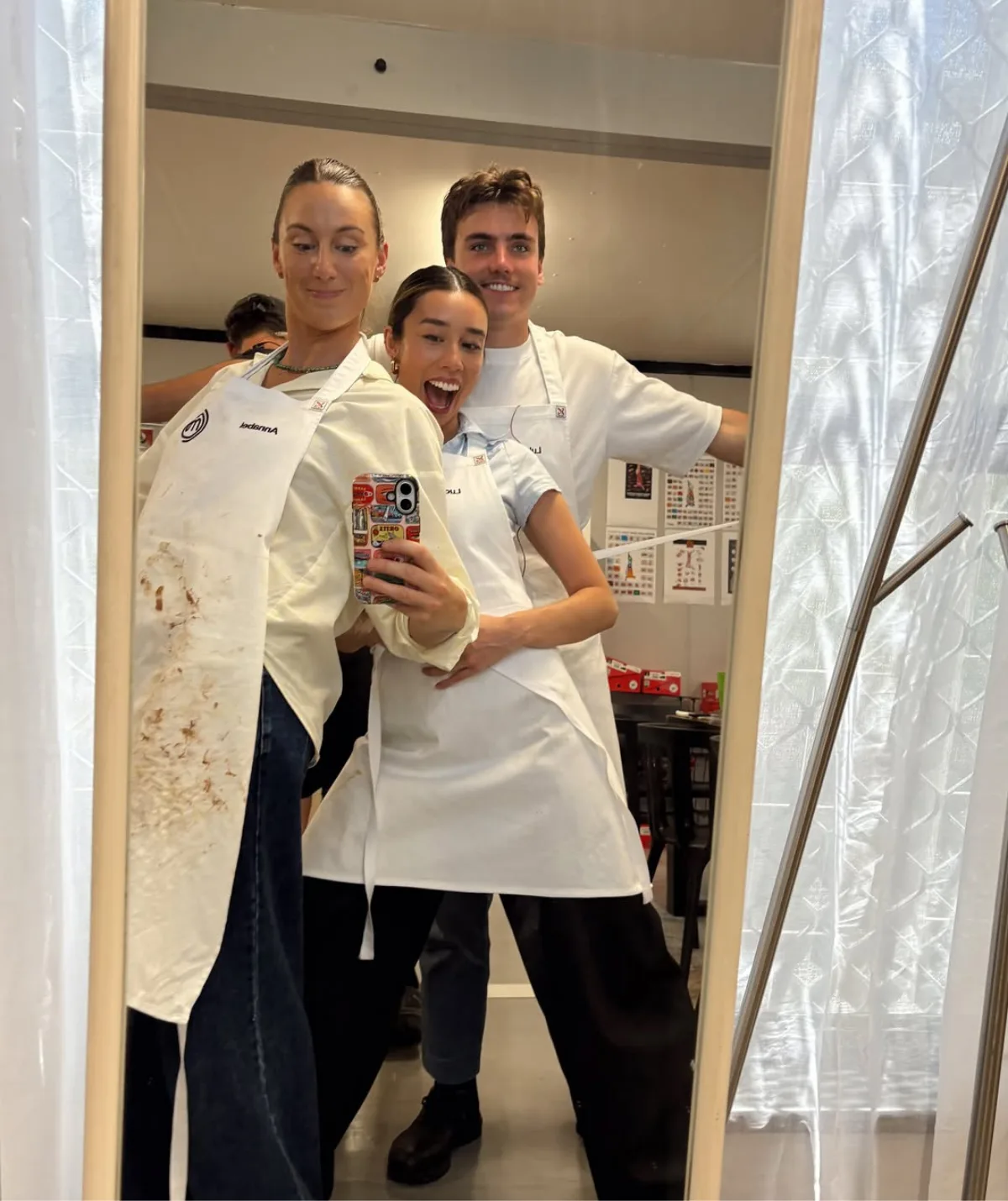 Annabel, Lucy and Luke from MasterChef Australia taking a mirror selfie with their aprons on.