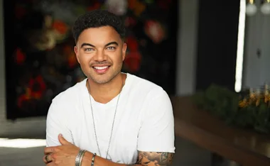 Guy, in a white t-shirt, smiling, with a dark background