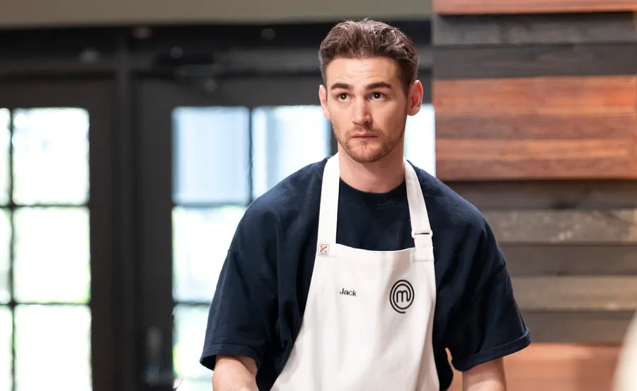 MasterChef Australia's Jack Hosking in the kitchen with black t-shirt and white apron.