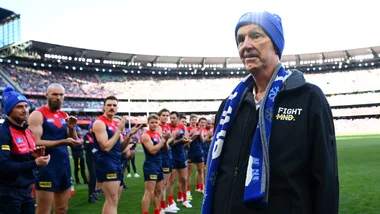 Neale Daniher pictured on AFL field with players clapping him on