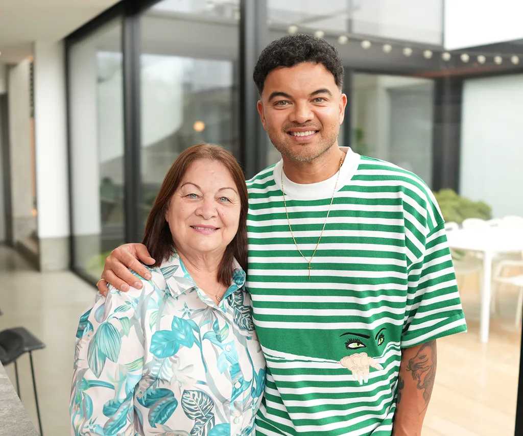 Guy, in a green striped top, stands next to his mother Nellie, in a green patterned outfit