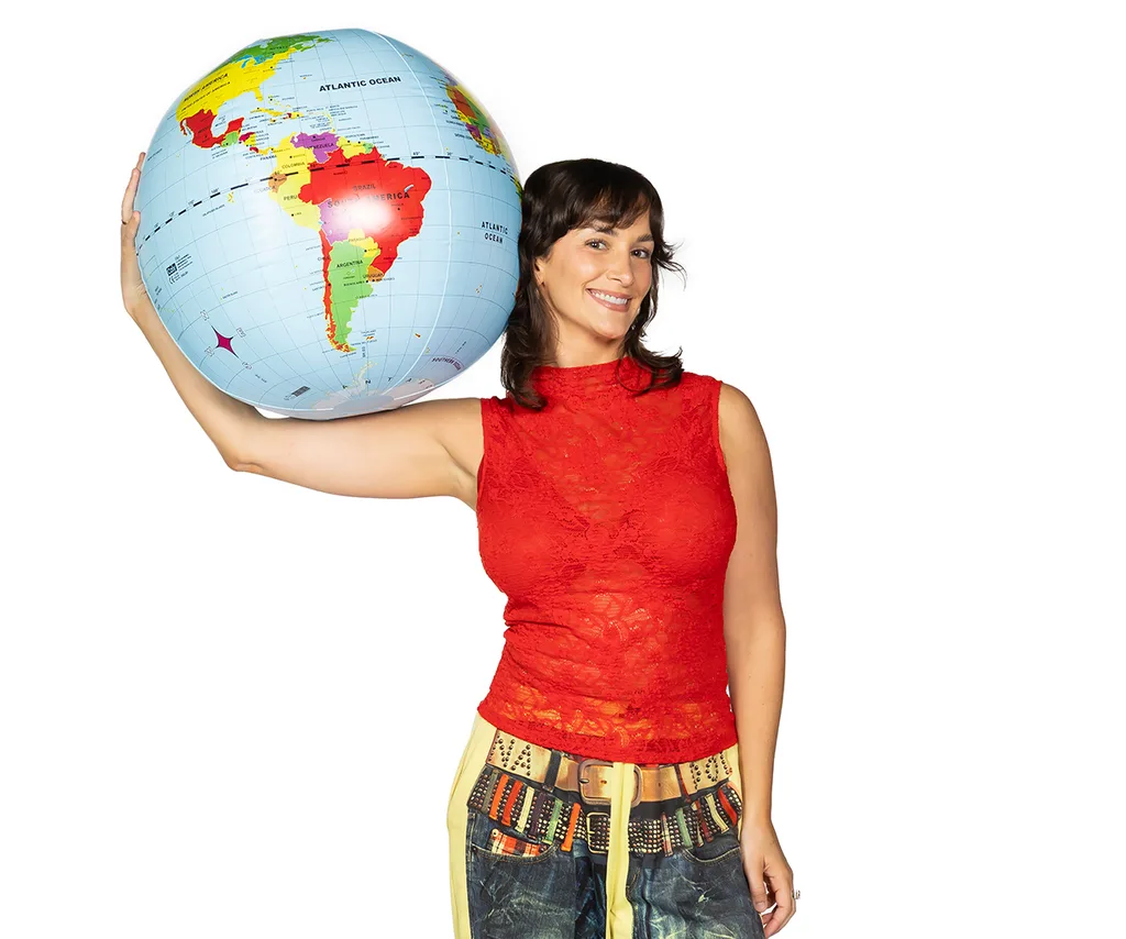 Lucinda, in a red sleeveless top, balances the world on her shoulder.