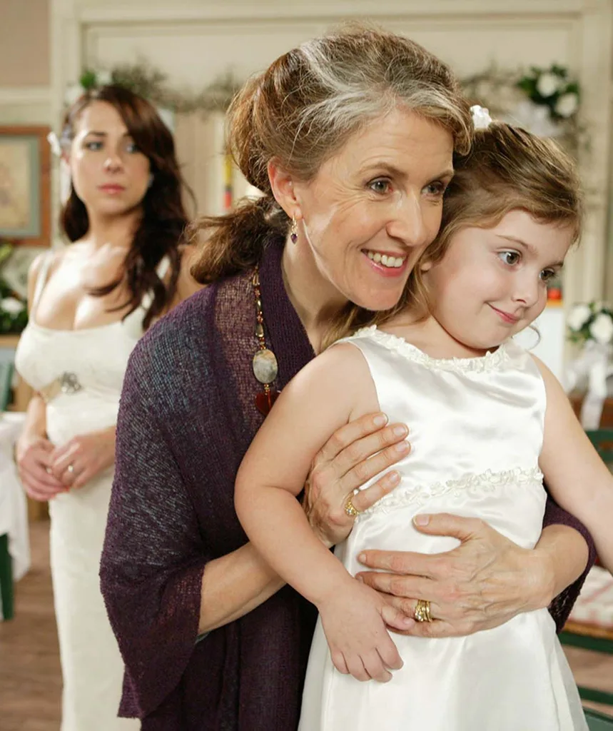Debra, in character as Pippa on Home And Away, holds a child dressed in white