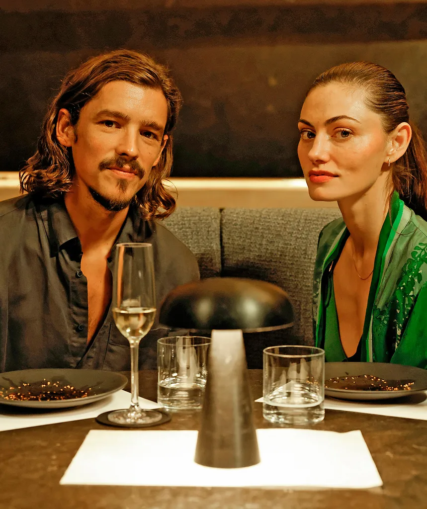 Brenton and Phoebe, in character as Ryan and Emily, sit at a restaurant
