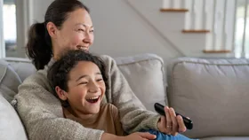 Mother and child on the sofa at home with tv remote