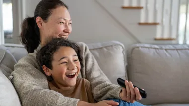Mother and child on the sofa at home with tv remote